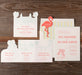 Set of wedding invitations with a flamingo design on a wooden surface