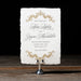 Rhea Save the Date card with ornate designs on a stand against a dark background