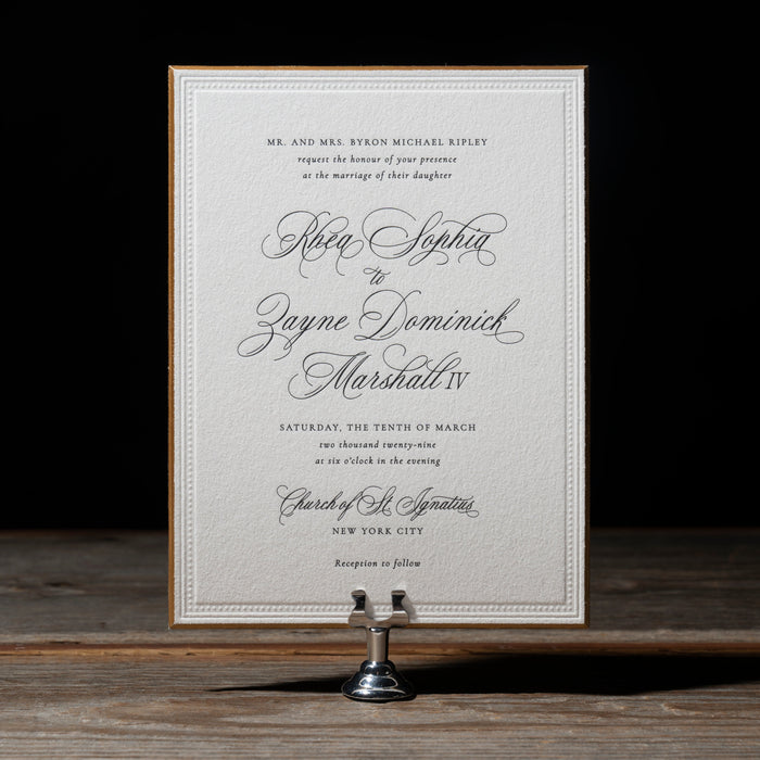 Rhea Wedding invitation card on a wooden surface with a dark background