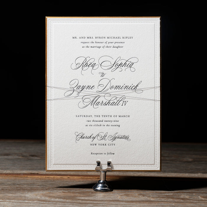 Rhea Wedding invitation card on a stand with a dark background