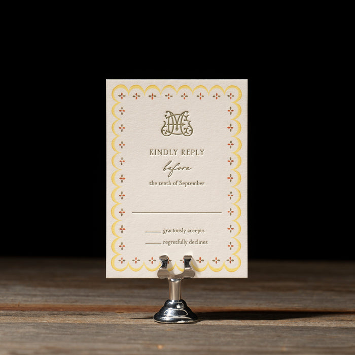 Royce RSVP card with decorative border on a stand against a dark background