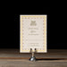 Royce RSVP card with decorative border on a stand against a dark background