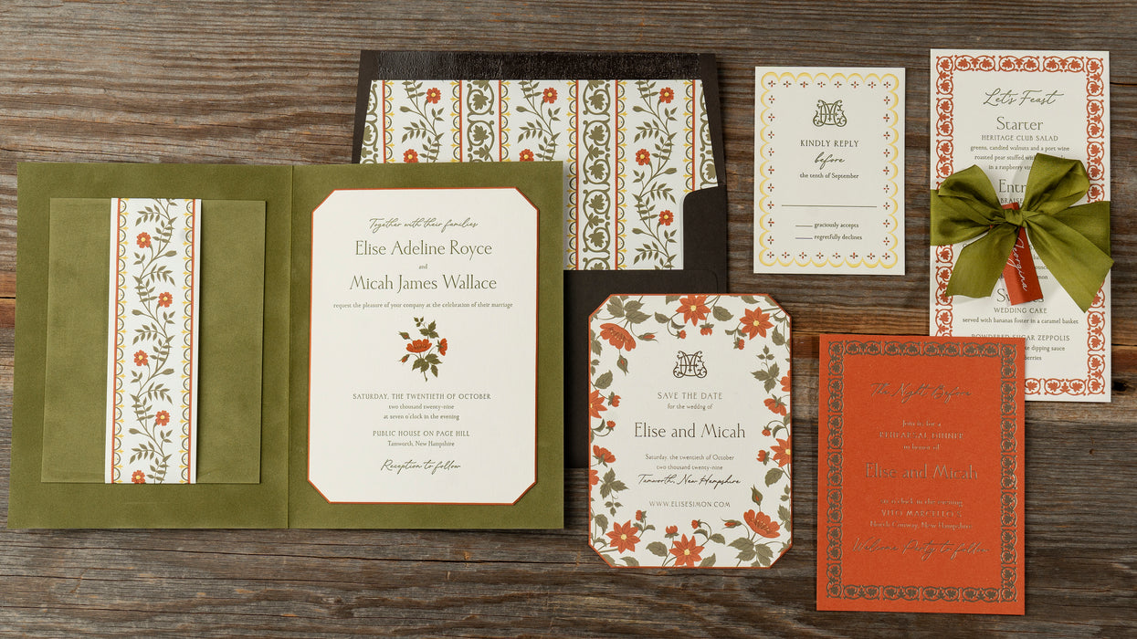 Collection of Royce wedding invitation suite pieces with floral designs on a wooden surface