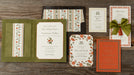 Collection of Royce wedding invitation suite pieces with floral designs on a wooden surface