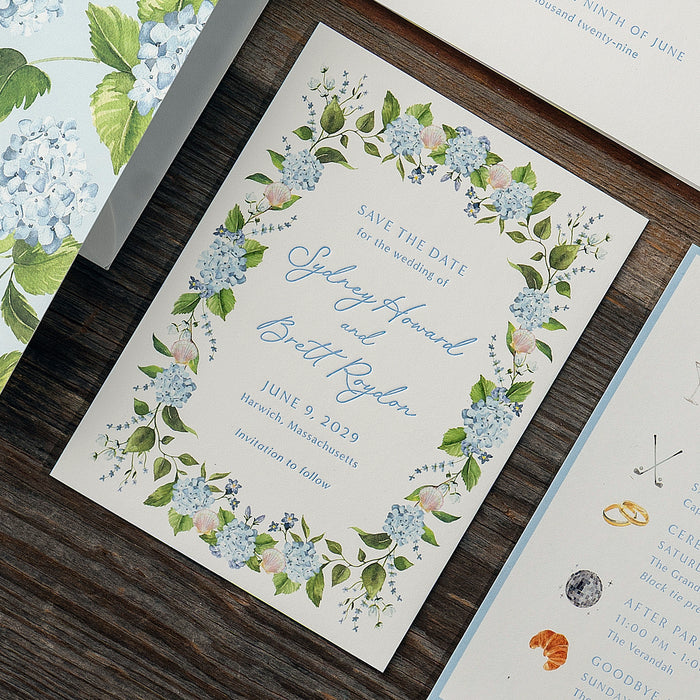 Roydon Save the Date with floral hydrangea design on a wooden surface