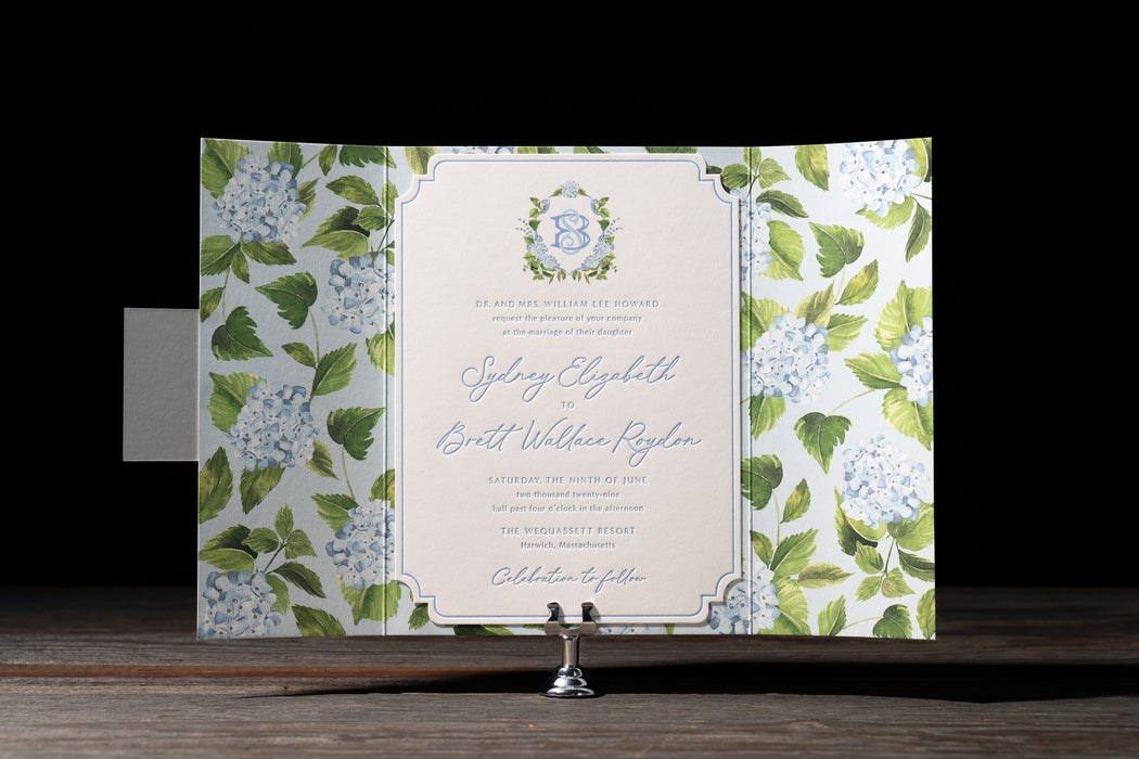 Roydon wedding invitation card with floral design on a stand against a dark background