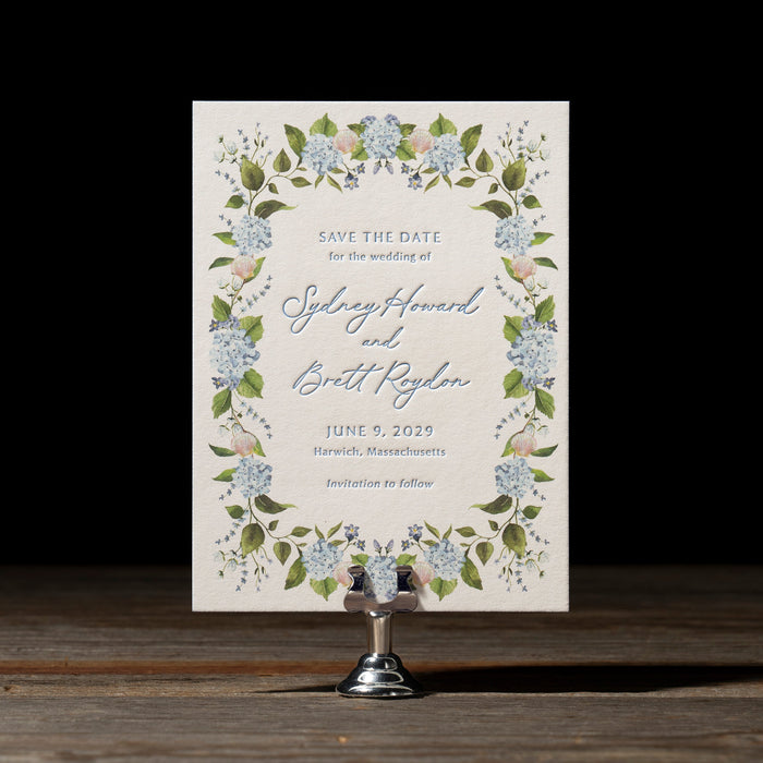 Roydon  save the date card with floral design on a stand against a dark background