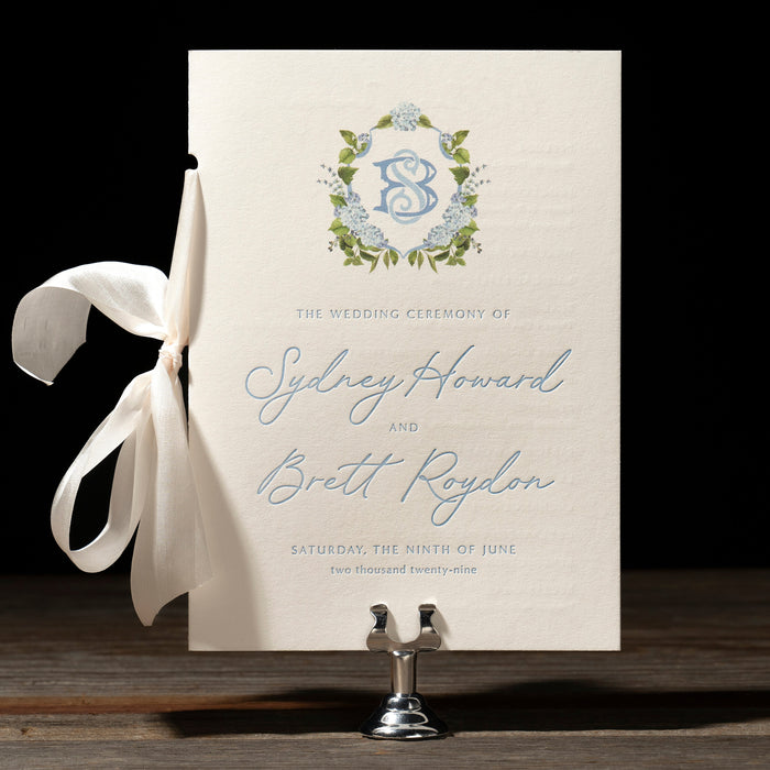 Roydon wedding program with blue hydrangea crest.