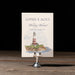 Ryann v2 wedding events card with lighthouse design on a stand against a dark background