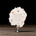 Round white details card with colorful graphics and text on a stand against a dark background