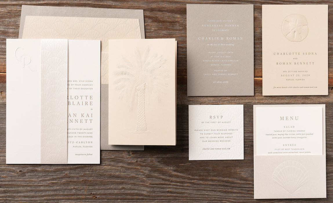 Set of wedding invitations and stationery items from Sedna Suite on a wooden surface
