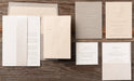 Set of wedding invitations and stationery items from Sedna Suite on a wooden surface