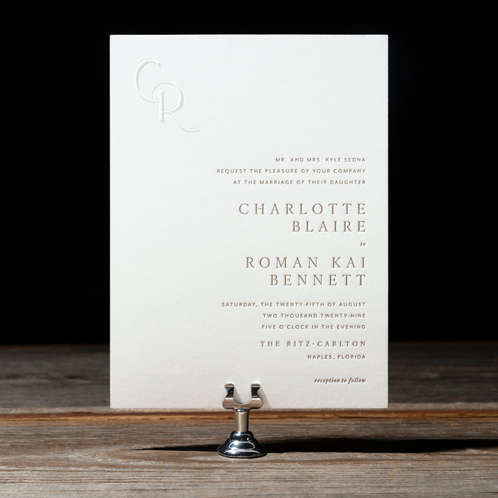 White Sedna wedding invitation card on a wooden surface with a black background