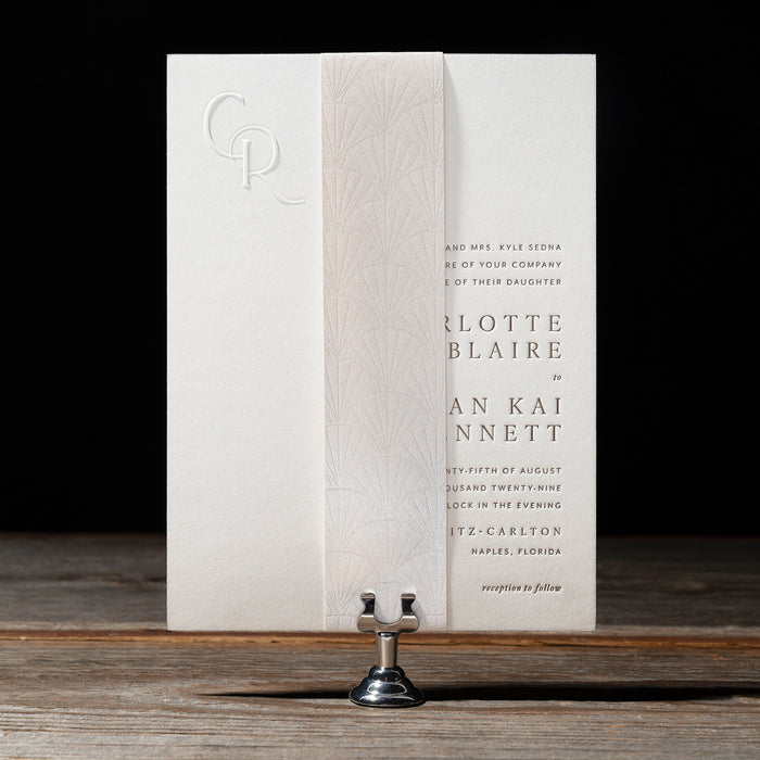 Letterpress Sedna wedding invitation on a wooden surface with a dark background