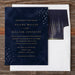 Navy blue Selene wedding invitation with gold text on a wooden surface