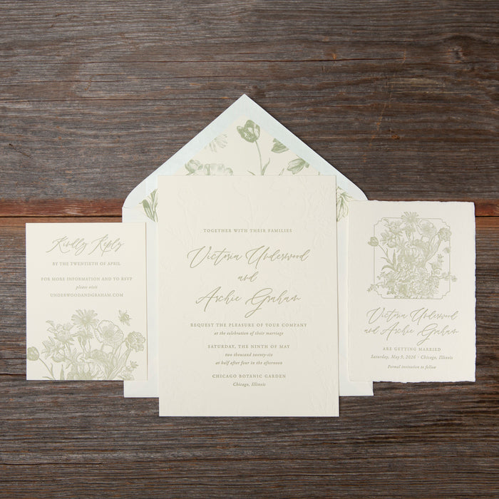 Set of wedding invitations with floral designs on a wooden surface