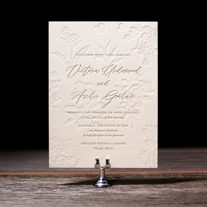 Invitation card with floral design on a stand against a dark background